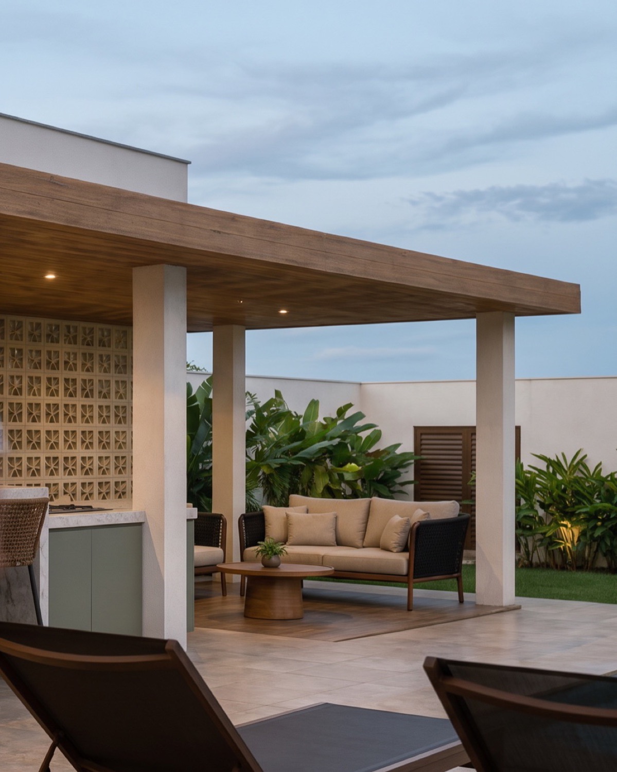 Varanda com parede de cobogó, estar externo e jardim ao fundo