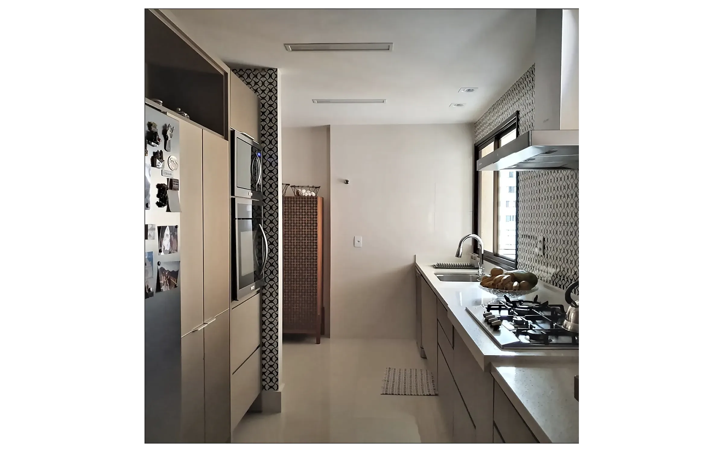 Foto da cozinha pronta, vista do corredor, com armários altos à esquerda e a bancada sob a janela à direita